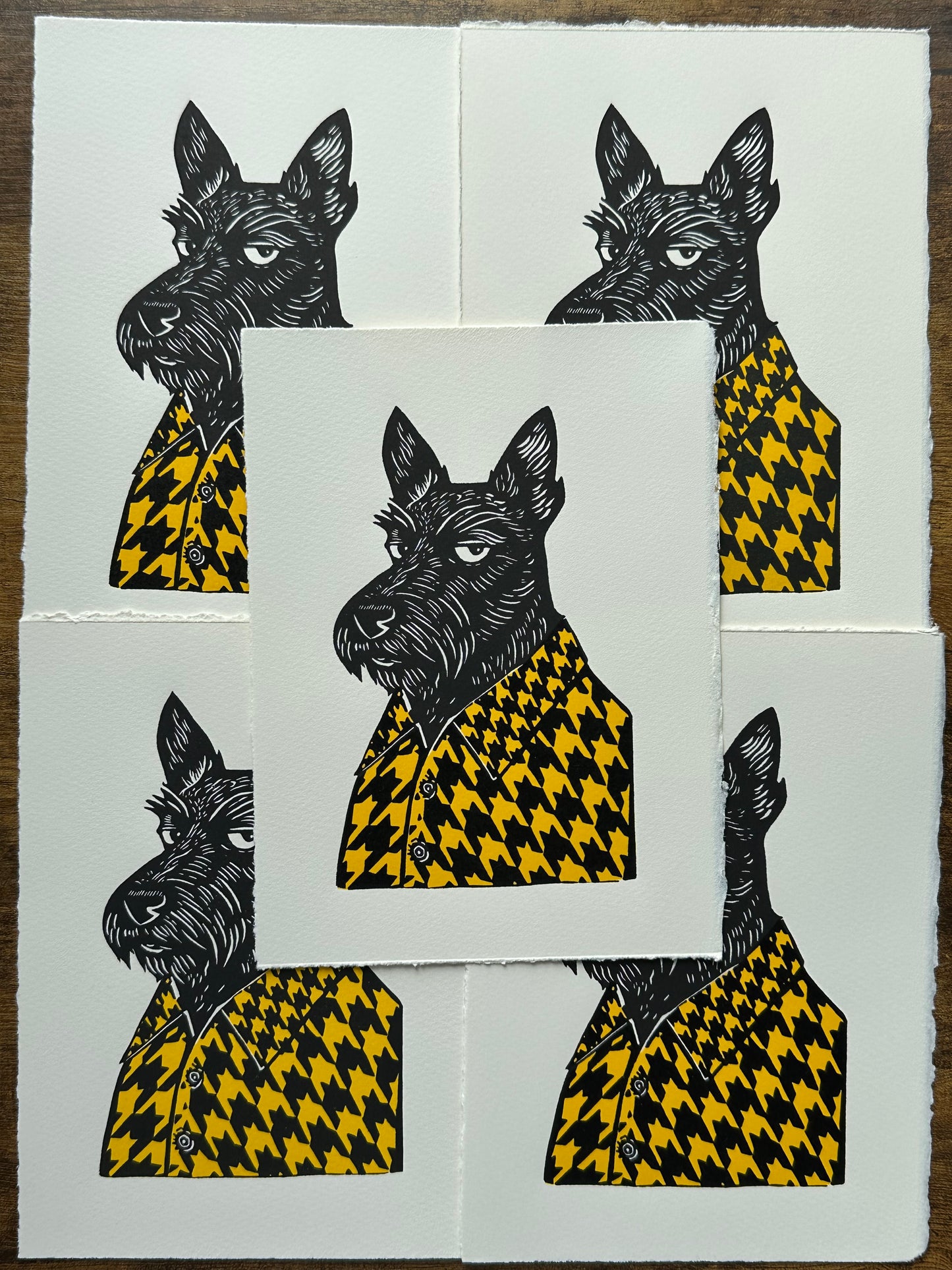 Black and white linocut print of a Scottish terrier wearing a houndstooth-patterned coat in yellow, showcasing bold textures and classic design.