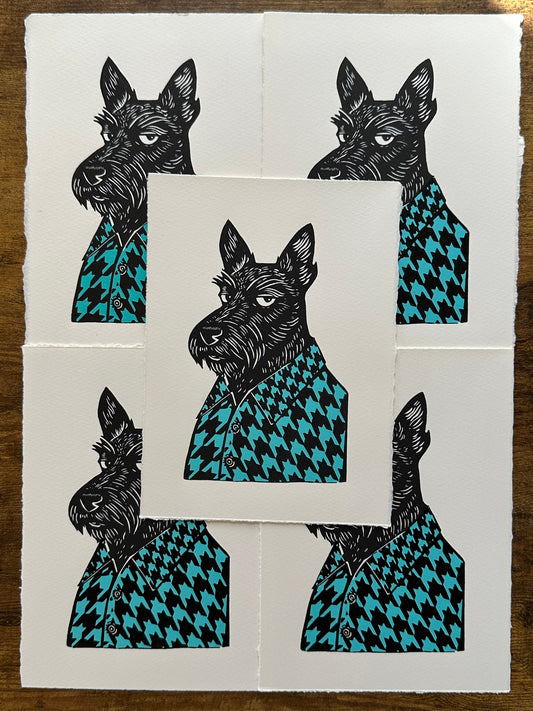 Black and white linocut print of a Scottish terrier wearing a houndstooth-patterned coat in blue, showcasing bold textures and classic design.