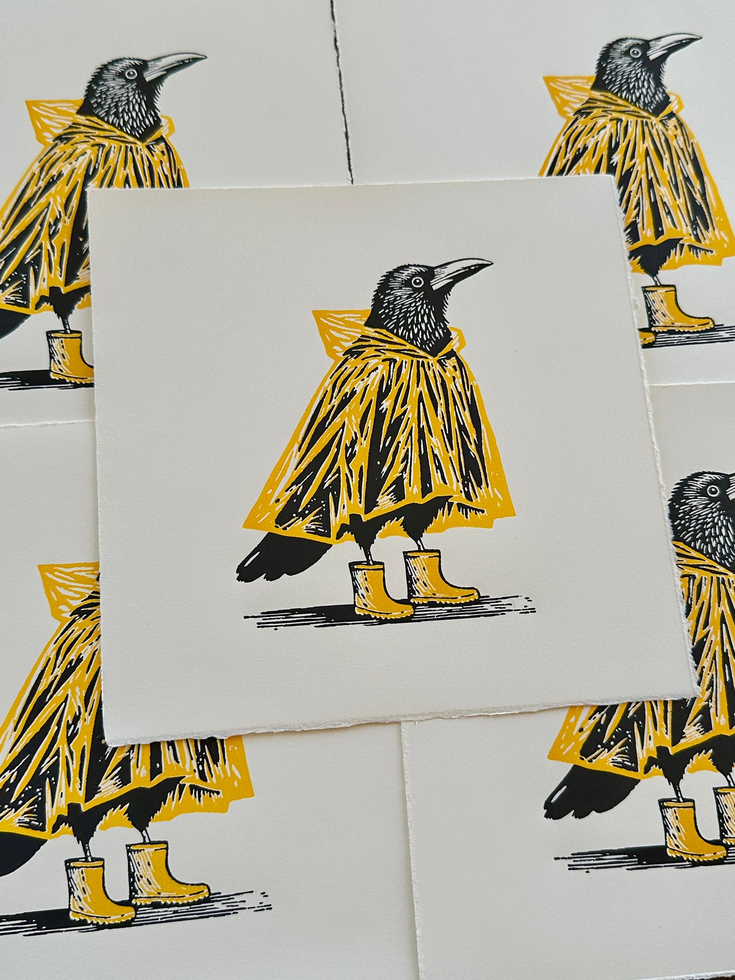 Linocut print of crows wearing yellow raincoats and boots on a white background