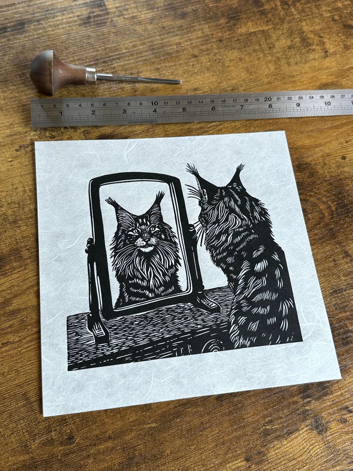 A black and white image of a cat, a maine coon looking at its reflection in a mirror, a perfect gift for cat lovers, wonderful linocut print.