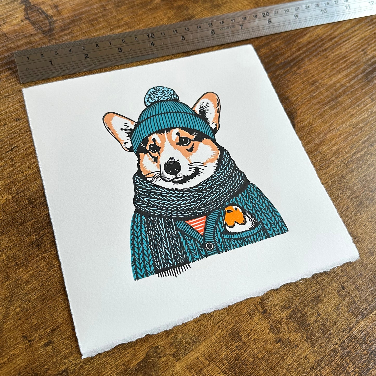 A linocut print of a corgi and robin, with a ruler for scale