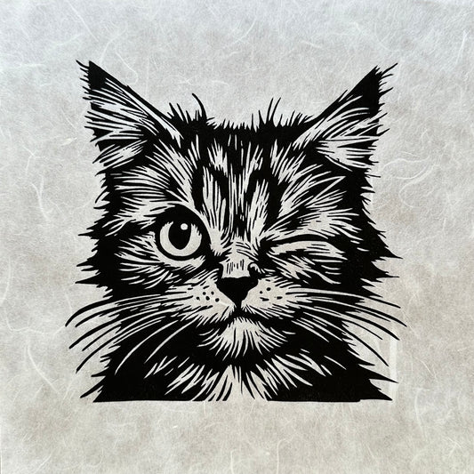 Linocut print of a playful cat winking, with bold, textured lines and a cheeky expression.