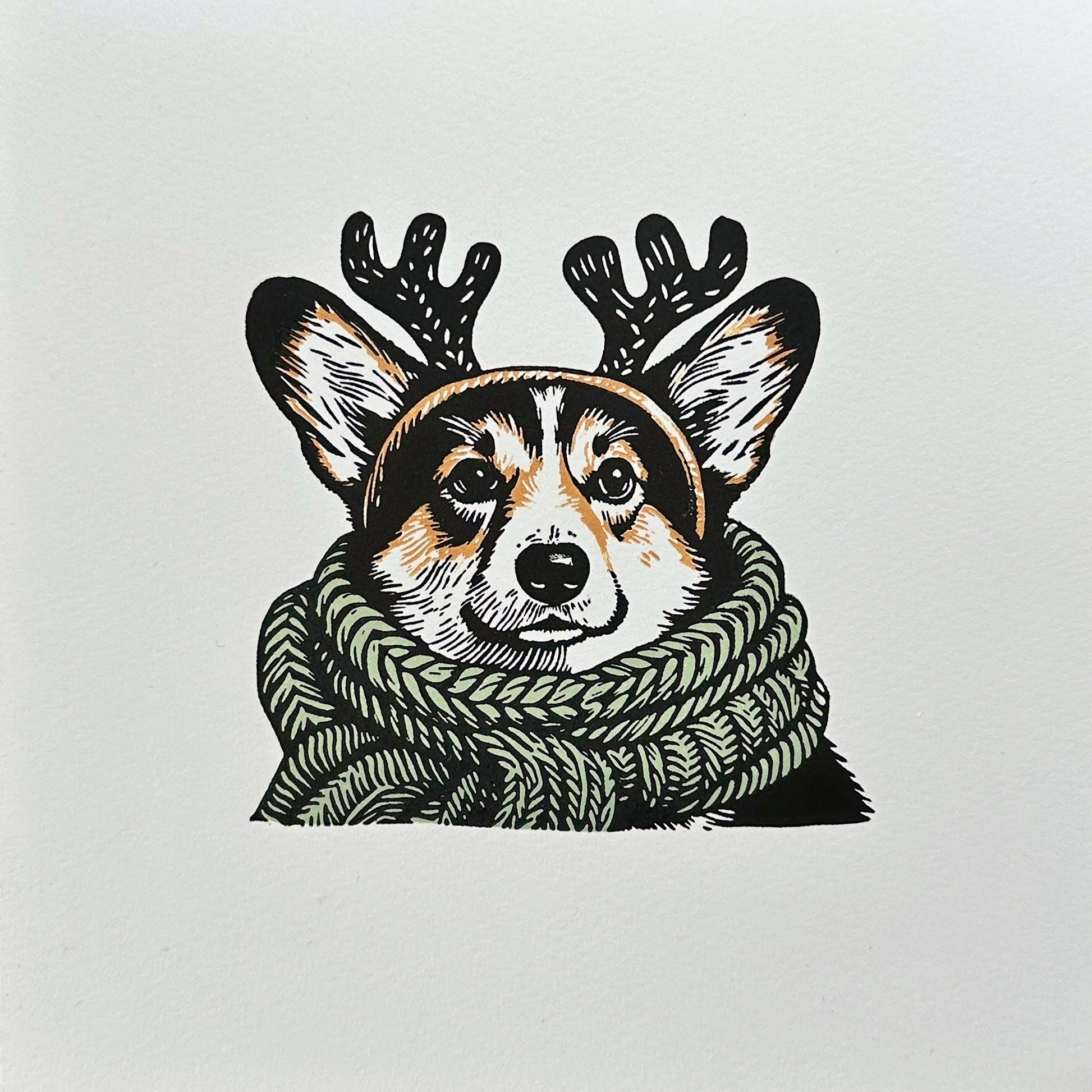 Multi-colour linocut print of a tricolour Pembroke corgi, predominantly black, white, and tan, adorned with an oversized, sage green knitted scarf wrapped around its neck. The corgi is also wearing a headband with cute antlers, giving it a festive look. The print has a plain white background, which highlights the detailed and colourful depiction of the corgi. Perfect gift for a corgi dog lover and art lovers.