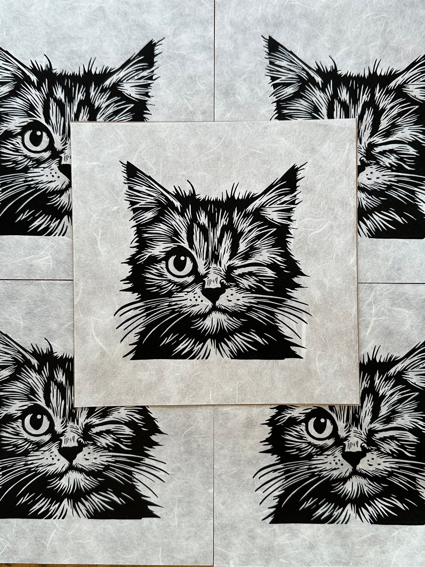 Linocut print of a playful cat winking, with bold, textured lines and a cheeky expression.