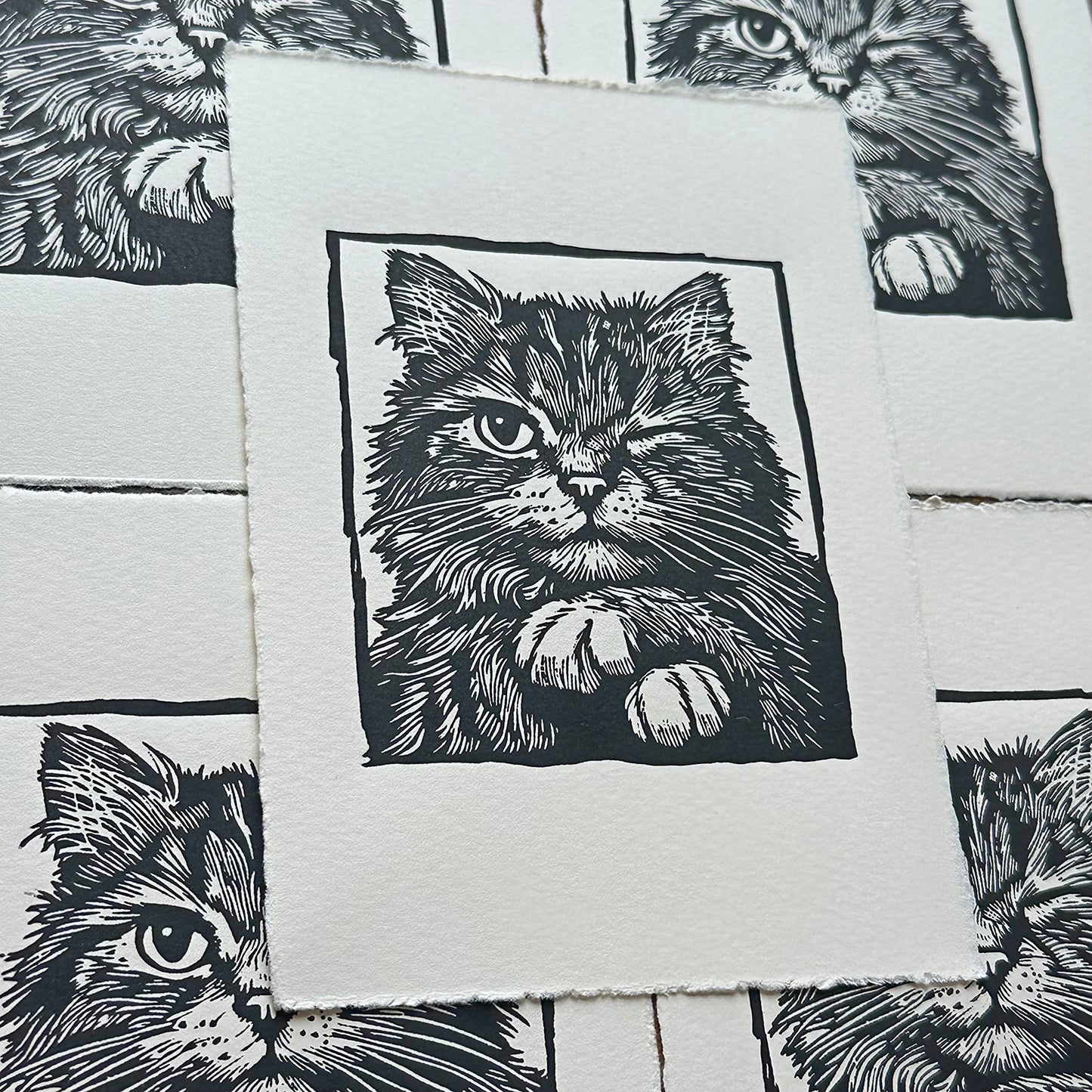 Linocut print of a cat with paws crossed and winking 
