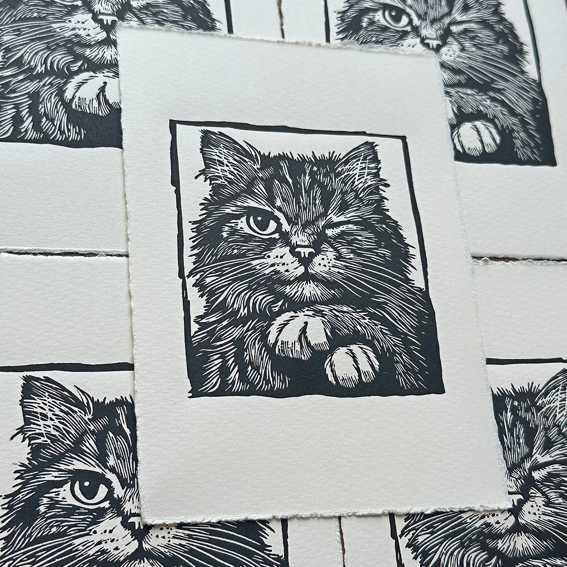 Linocut print of a cat with paws crossed and winking 