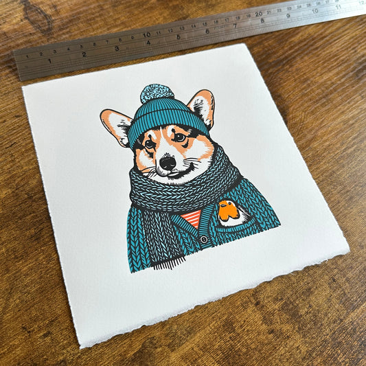 A linocut print of a corgi and robin, with a ruler for scale